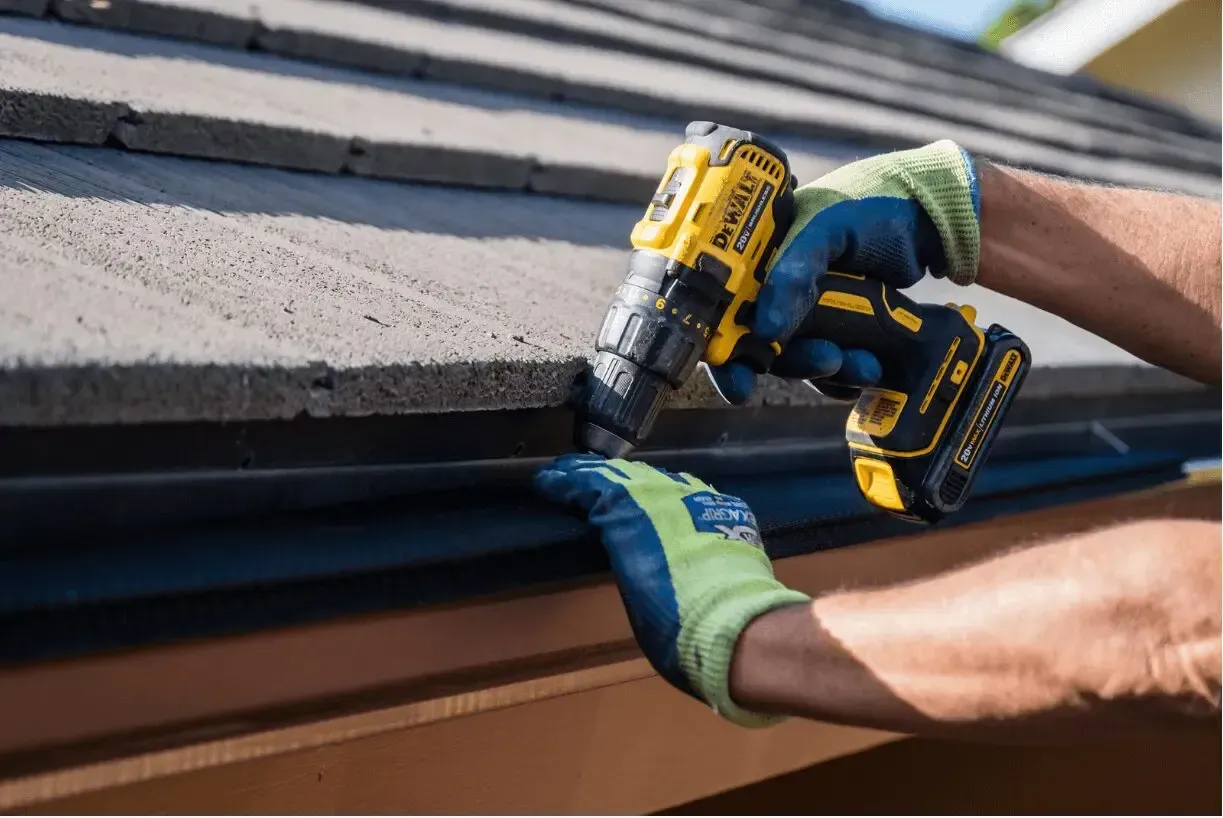A person is using a drill on a roof.