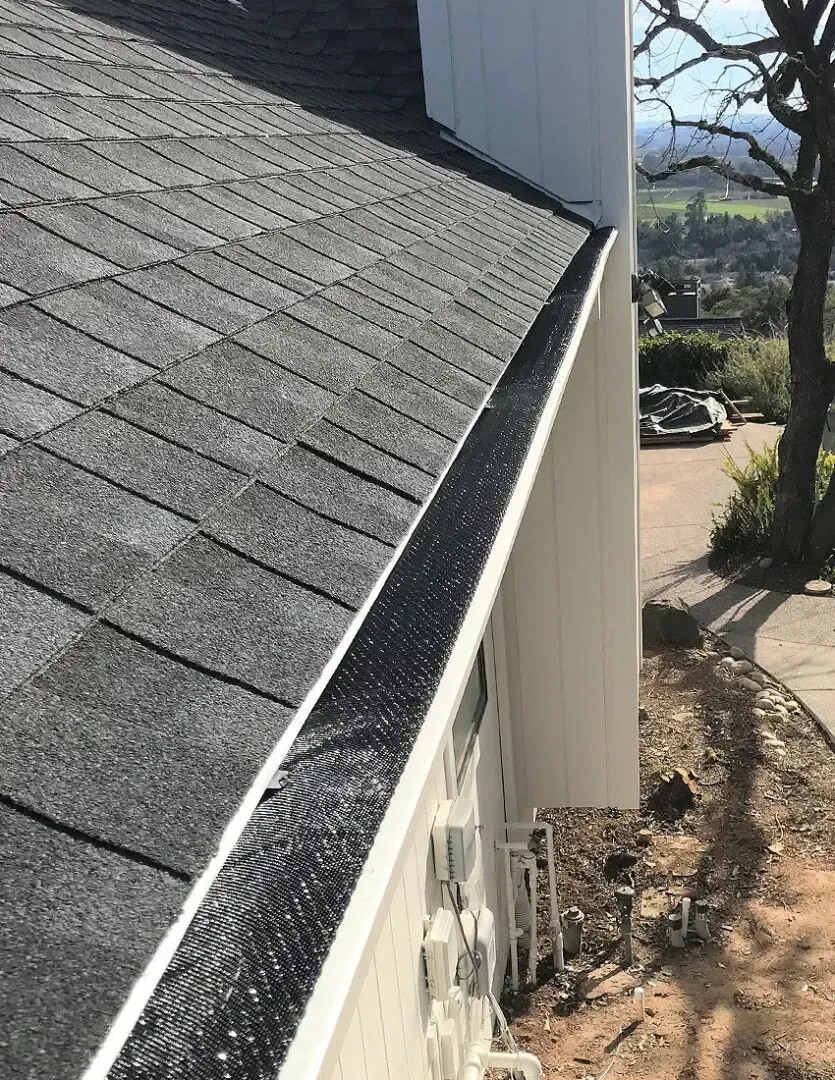 A close up of a gutter on the side of a house.