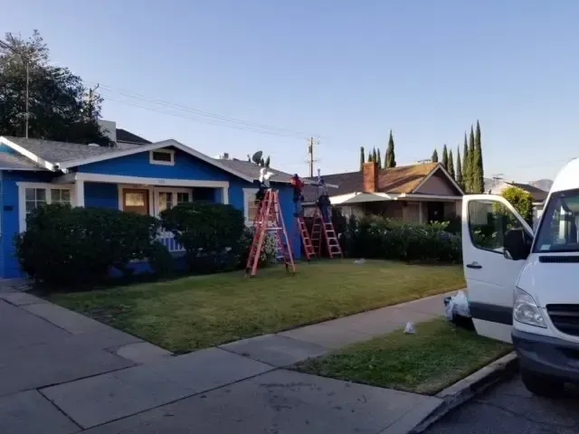 A white van is parked in front of a blue house