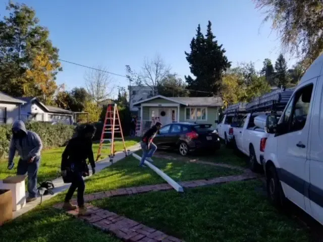A group of people are working on a roof in front of a house.