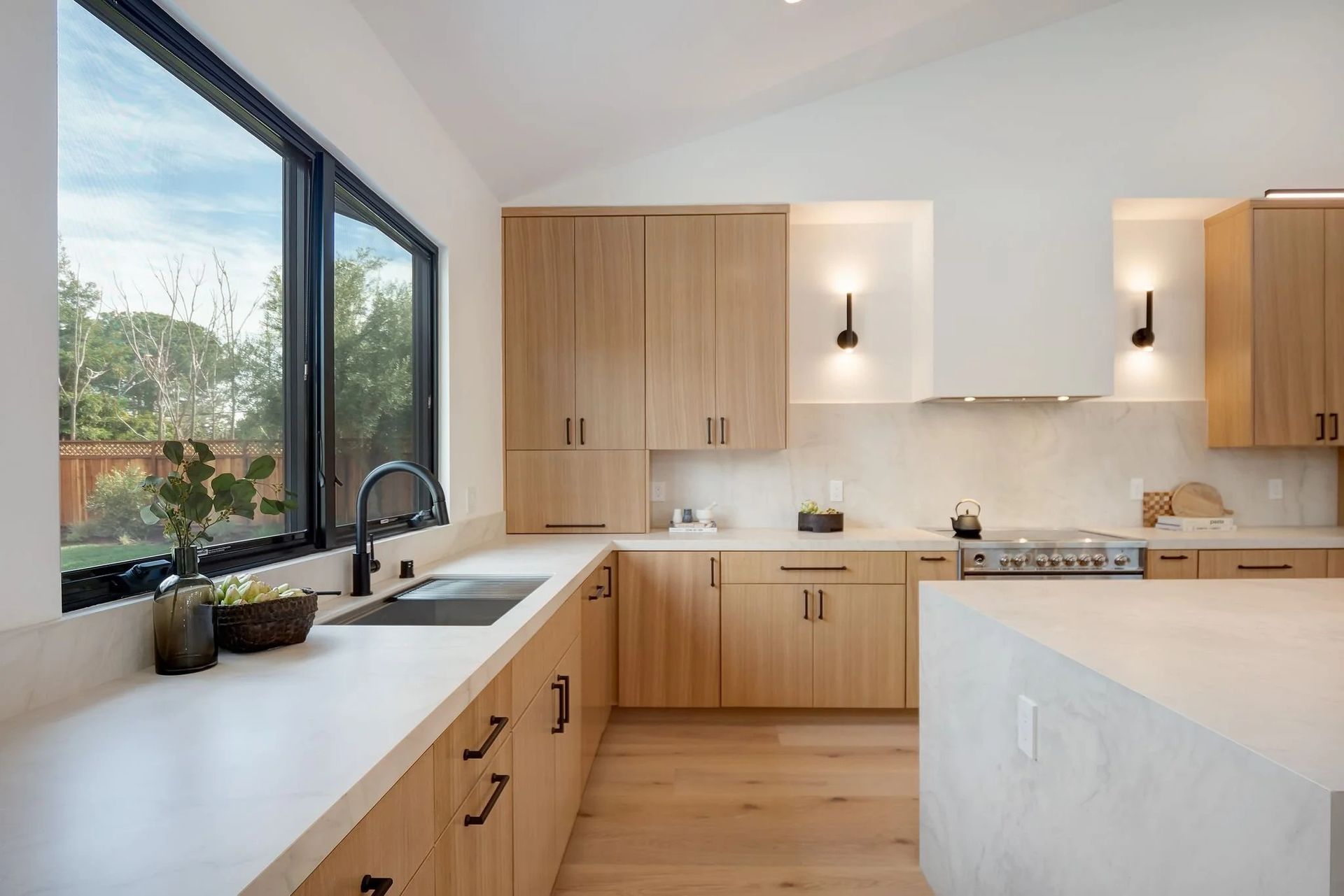 Modern kitchen with wood cabinets, light countertops, and large window.