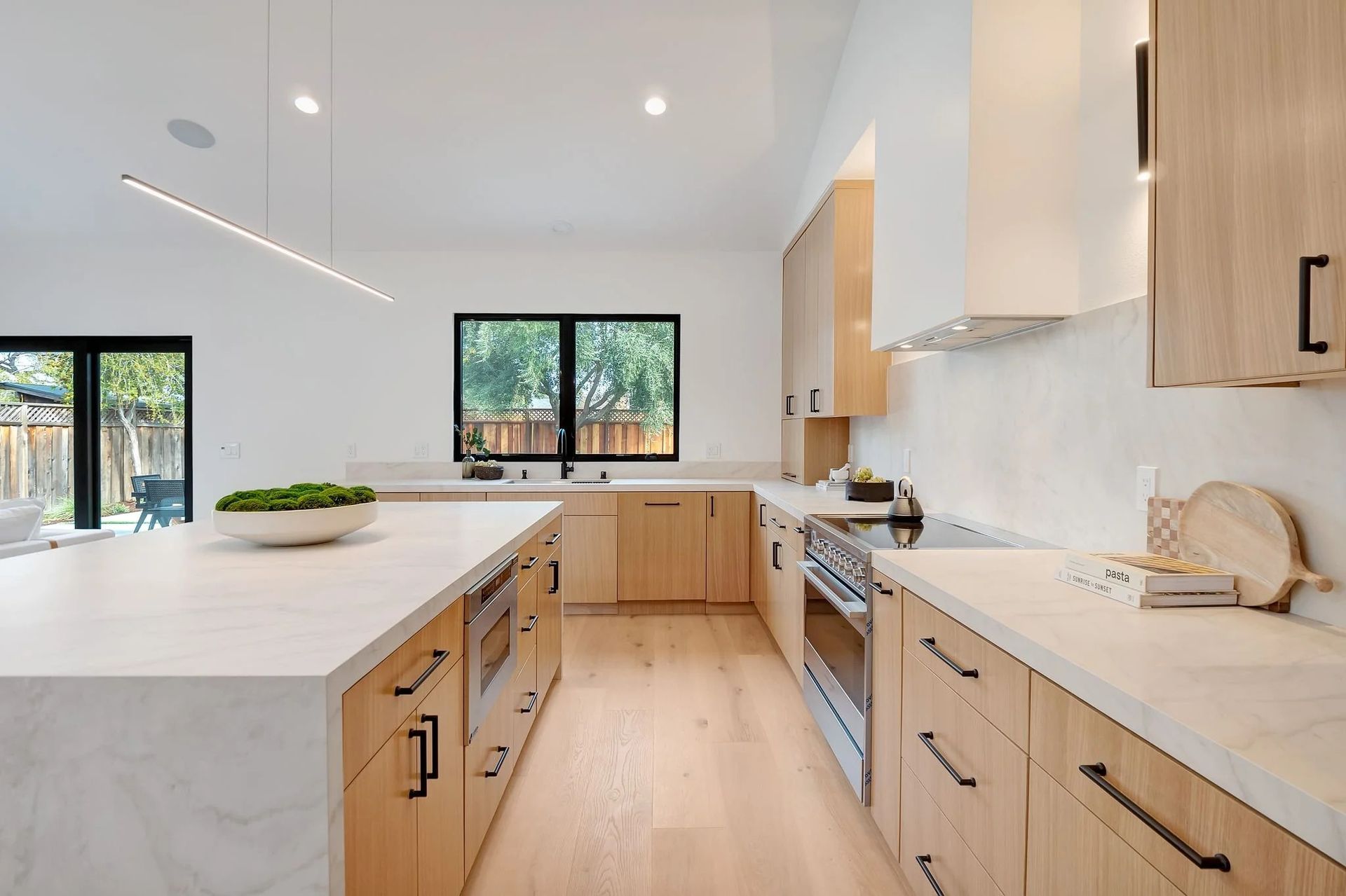 Modern kitchen with wood cabinets, white countertops, and a large island.