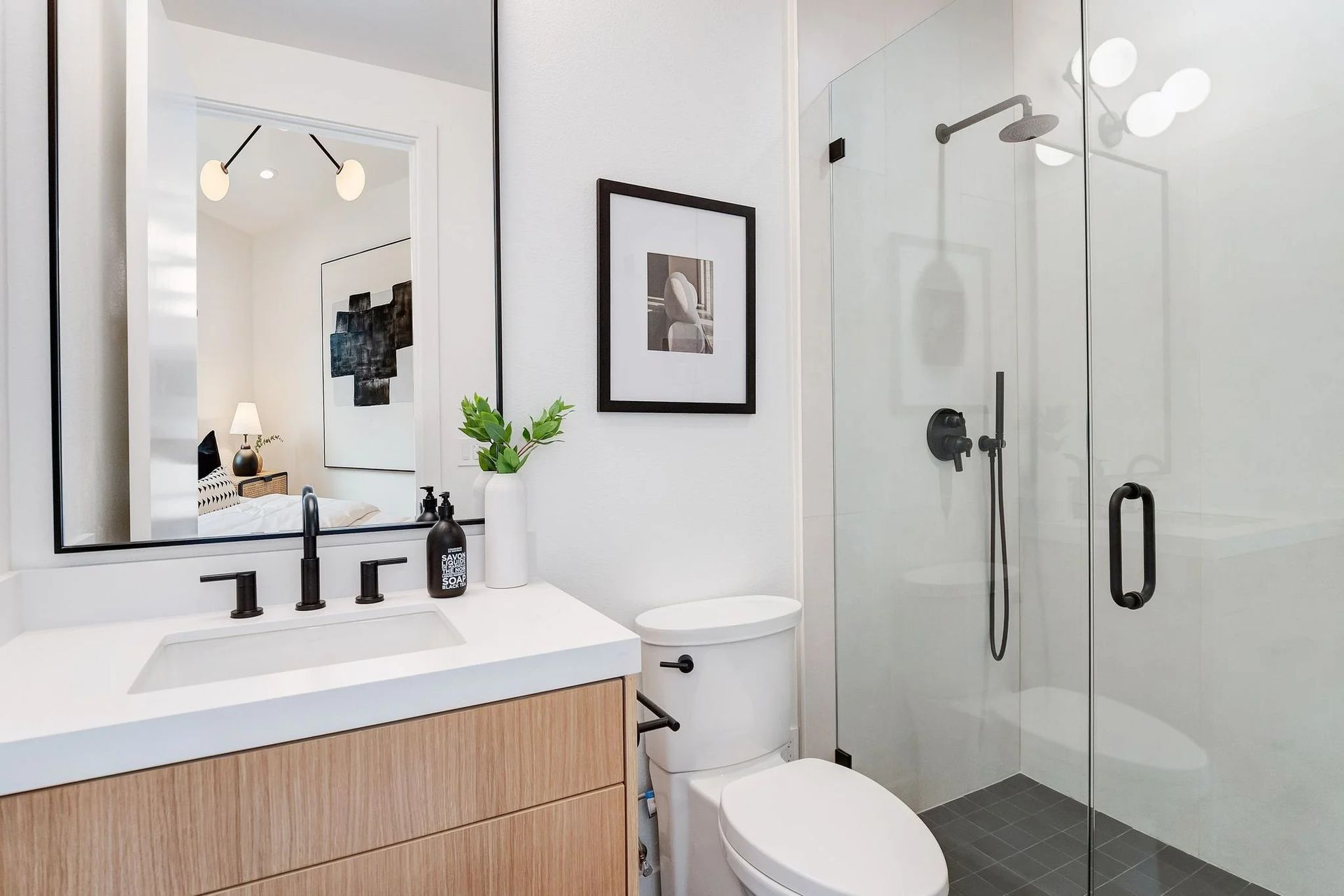 Modern bathroom with white walls, a glass shower, and wooden vanity.