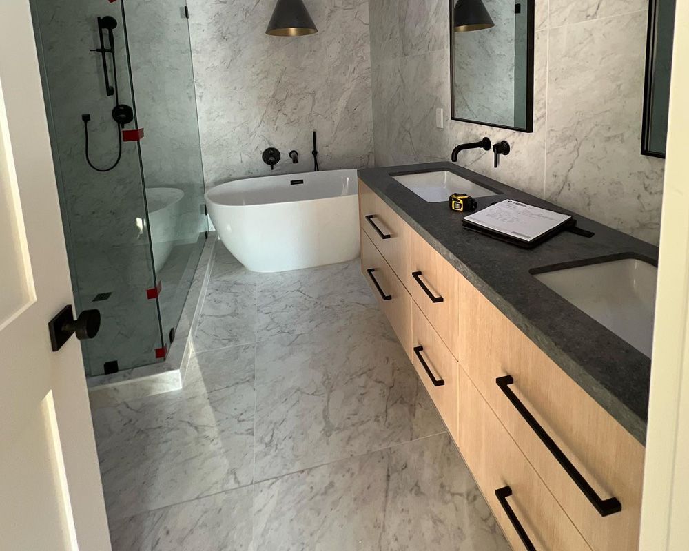 Modern bathroom with a freestanding tub, double sink vanity, and marble-look tile.