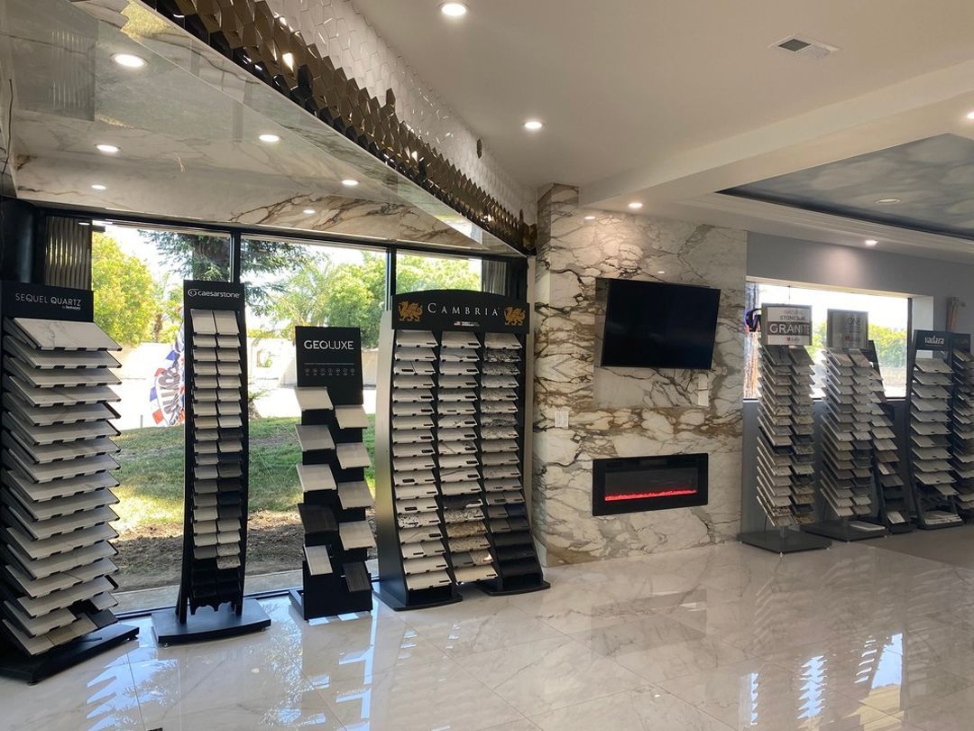 Tile showroom with tile sample displays. Natural stone accent wall, black framed windows, and shiny floor.