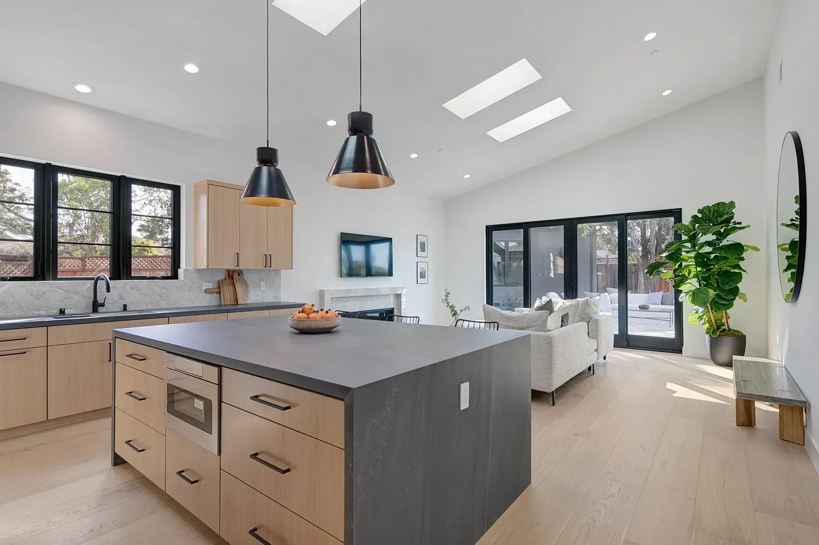 Modern kitchen with island, skylights, and open to a living area with a sofa.