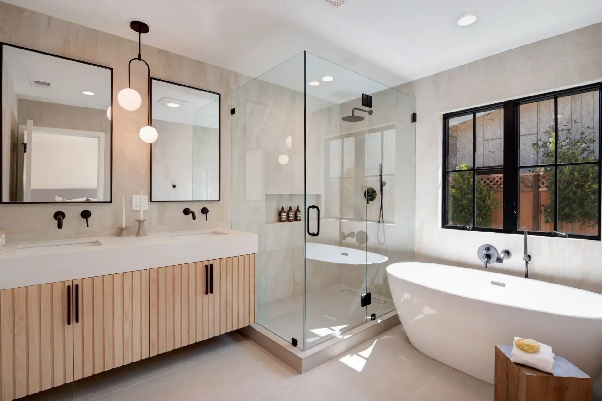 Modern bathroom with a soaking tub, shower, and double vanity with wood-tone cabinets and black fixtures.
