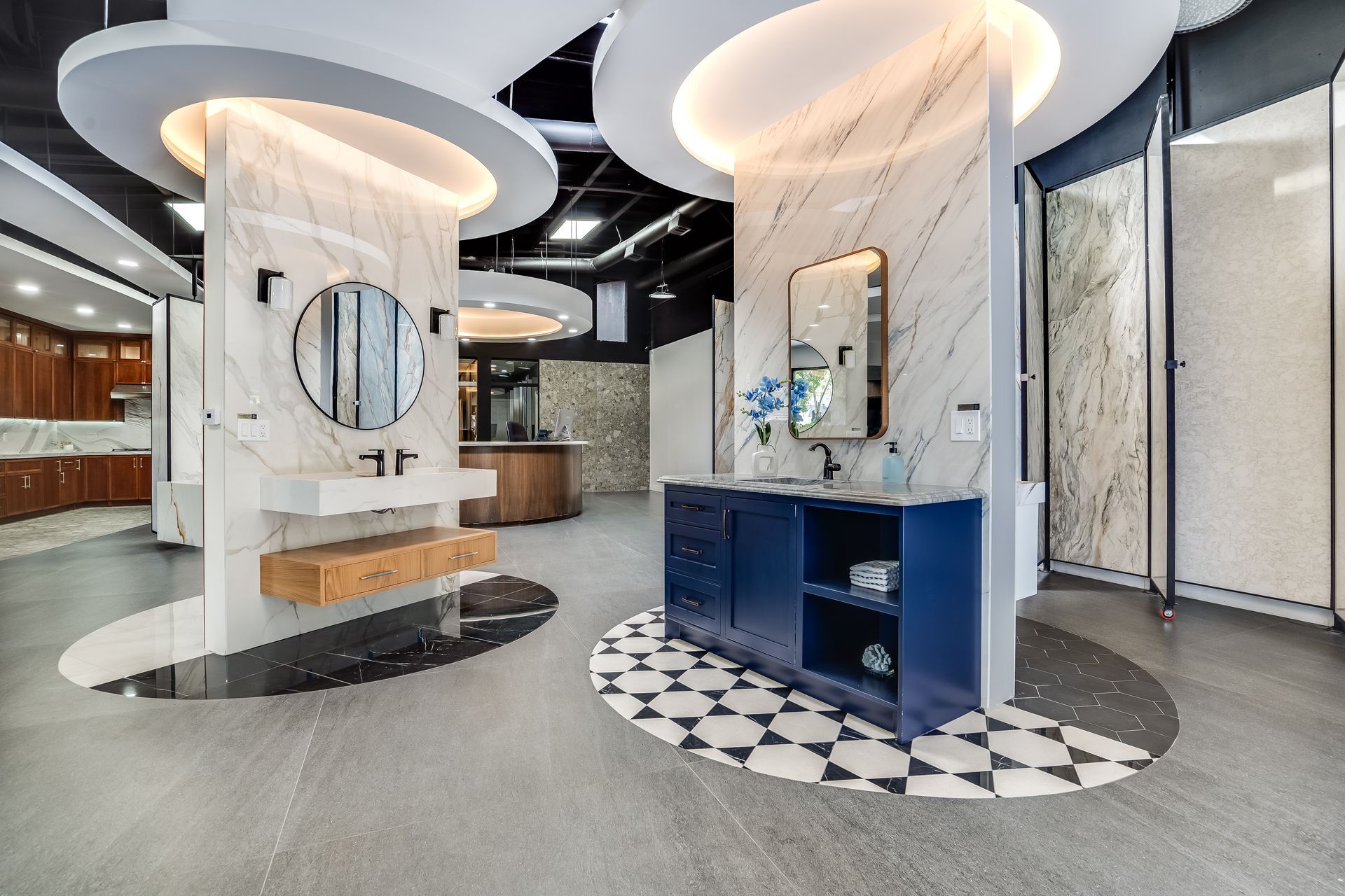 Bathroom showroom with displays featuring marble and cabinetry, black and white patterned floors.