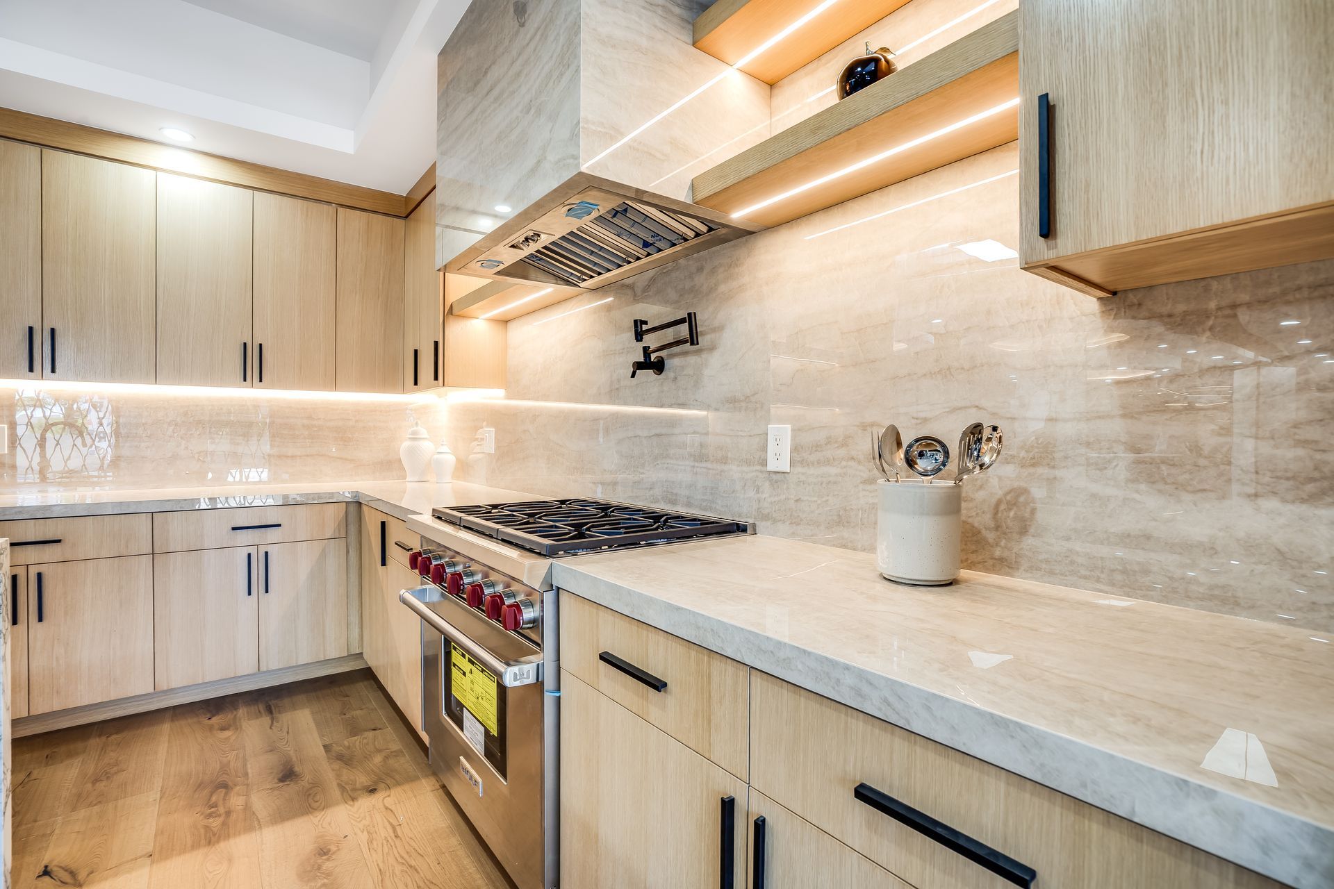 Modern kitchen with light wood cabinets, stainless steel appliances, and a neutral backsplash.