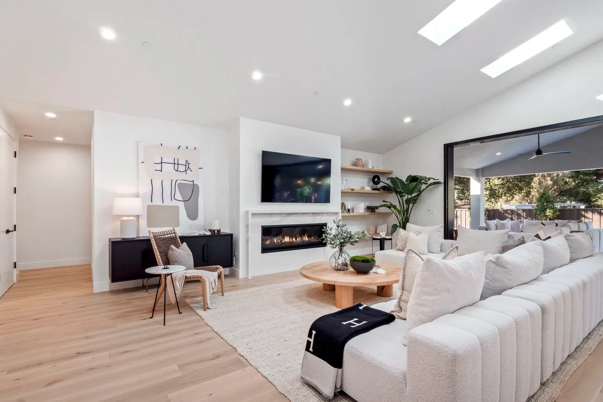 Bright living room with fireplace, TV, white couch, and sliding doors to outdoor patio.
