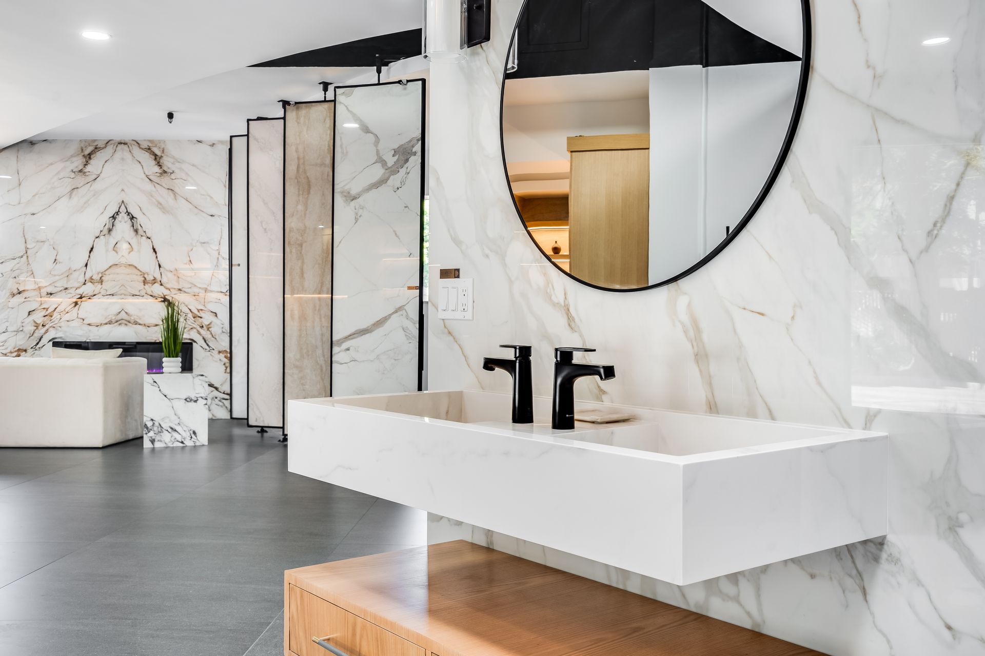 Bathroom with marble tile walls, floating sink, black fixtures, and large mirror.