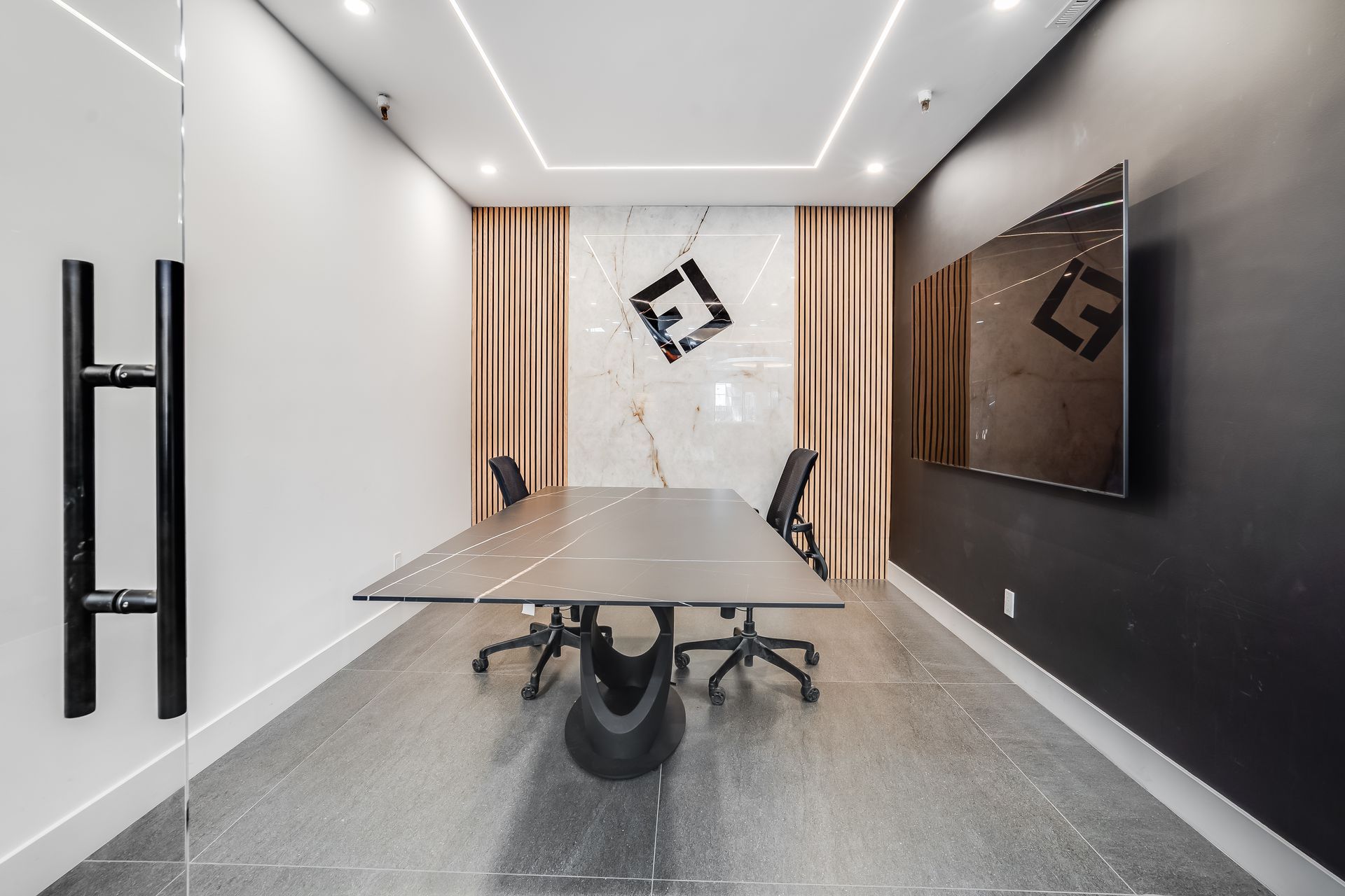 Reception desk in showroom. Curved brown base, light-colored top, computer, and two chairs under a circular recessed ceiling with lights.