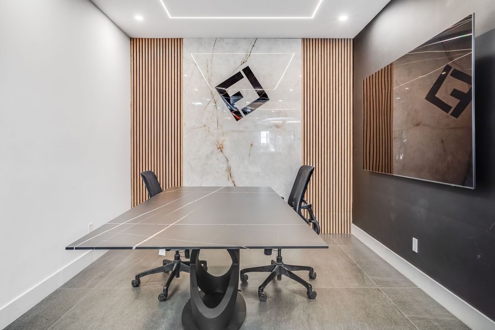 Modern conference room with a table, chairs, and decorative wall features, including a logo.