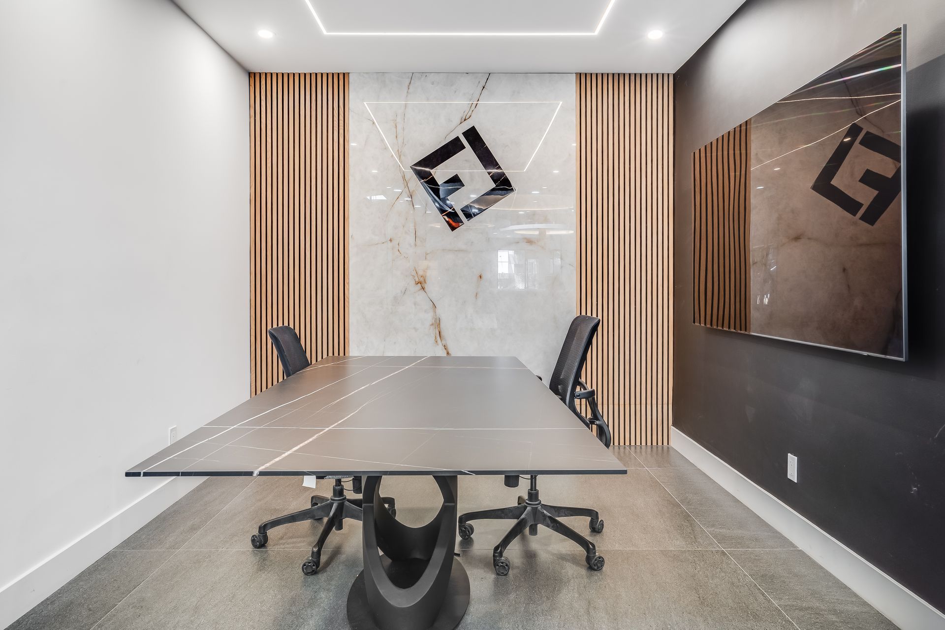 Reception desk in showroom. Curved brown base, light-colored top, computer, and two chairs under a circular recessed ceiling with lights.