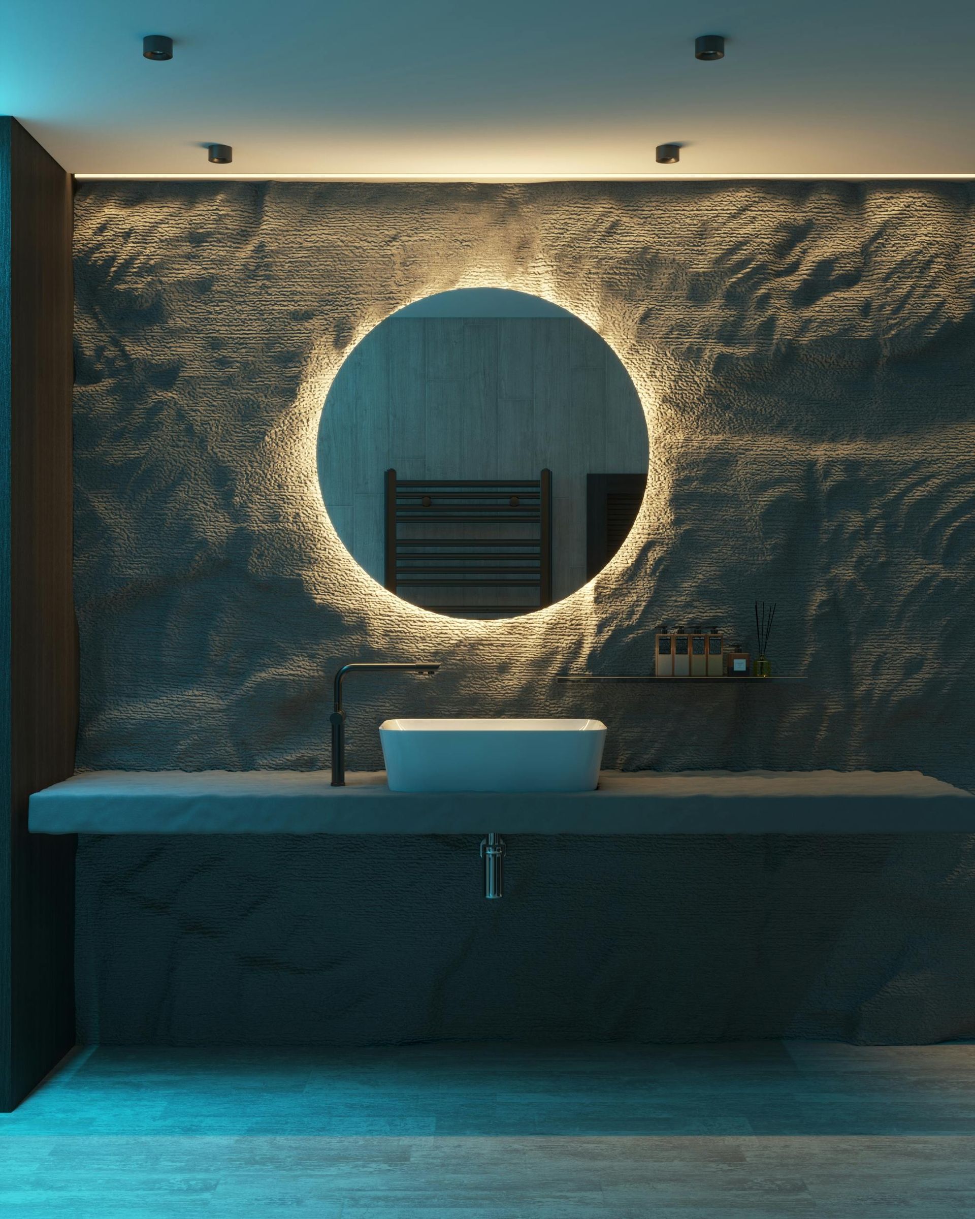 Bathroom with stone wall, circular mirror with illuminated border, rectangular sink, and black faucet.