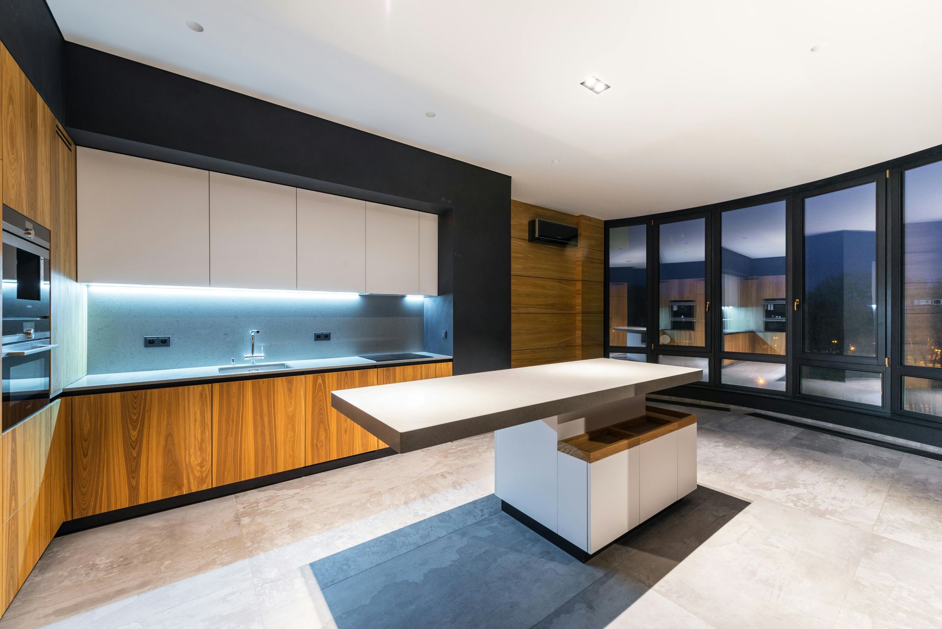 Modern kitchen with white and wood cabinets, large island, and floor-to-ceiling windows.