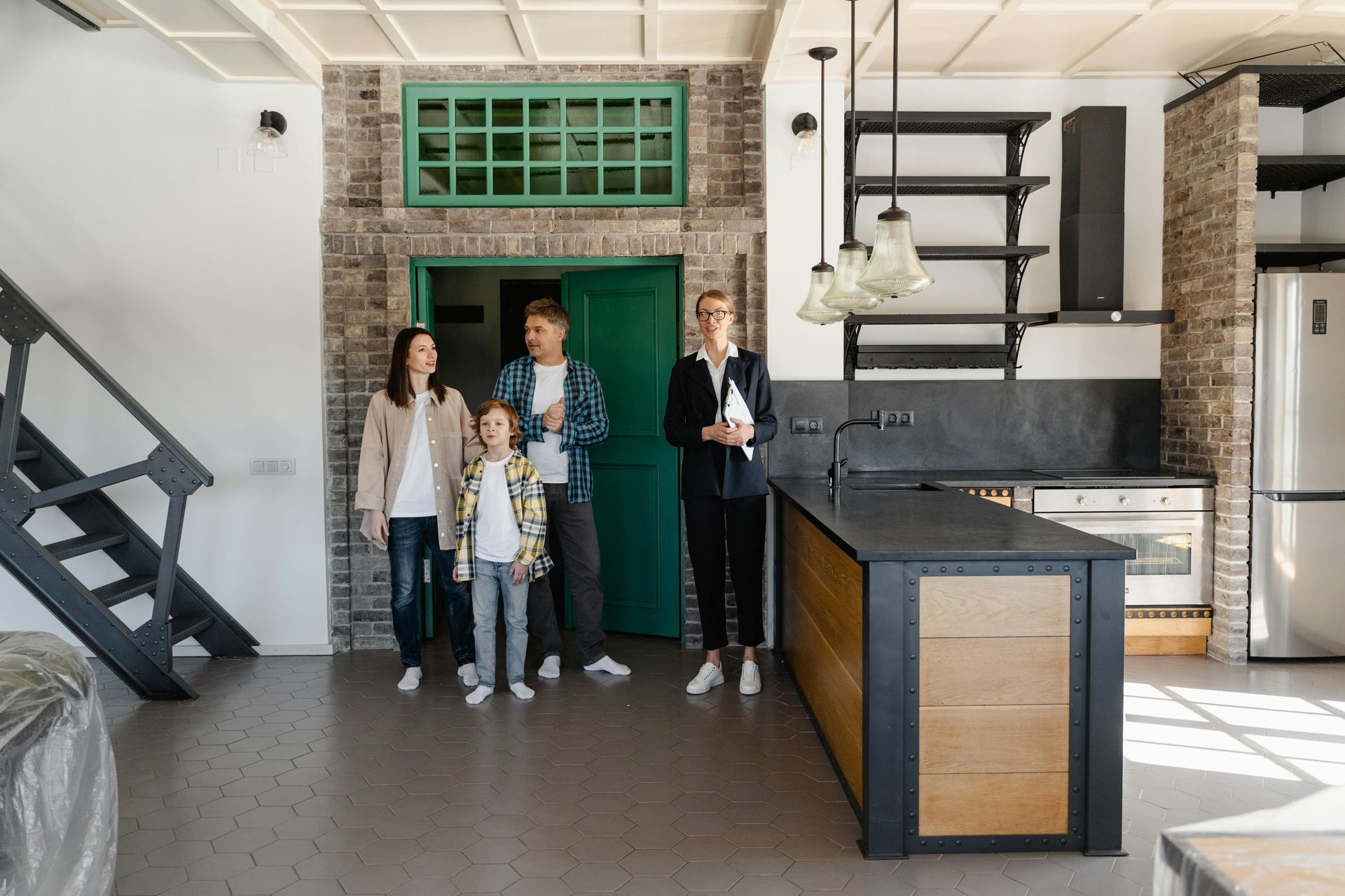 Family and realtor tour a modern kitchen with exposed brick.