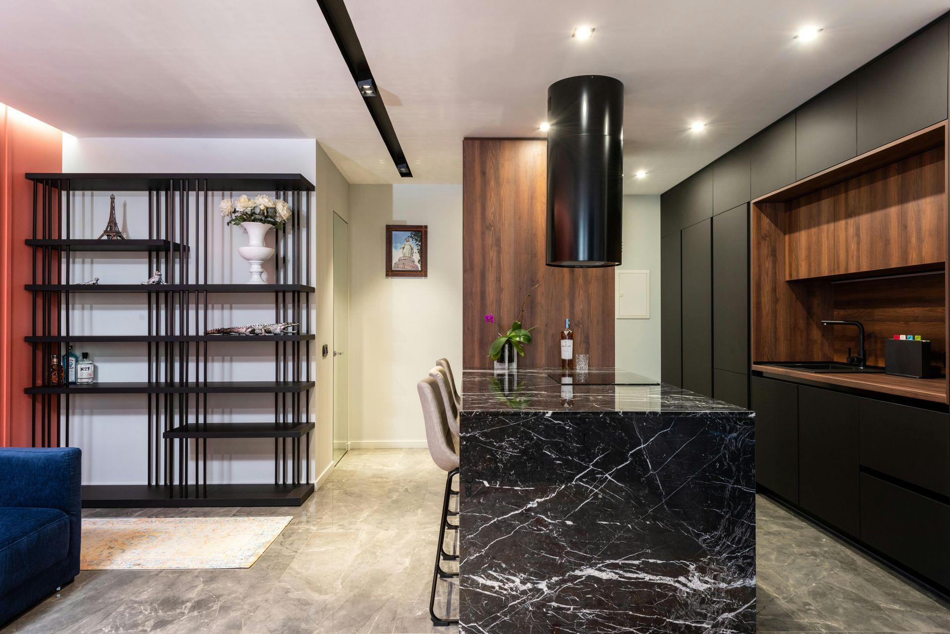 Modern kitchen with black marble island, black cabinetry, and wooden accents.