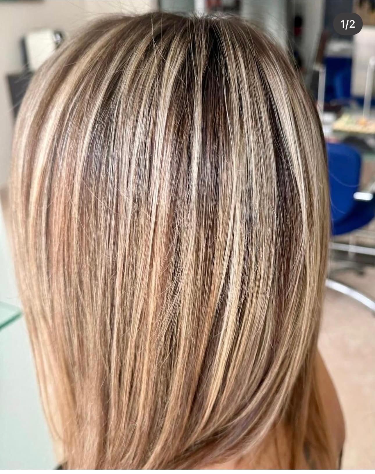 Capelli biondi scalati con mèches e colpi di sole scuri, visti di spalle in un salone di bellezza.