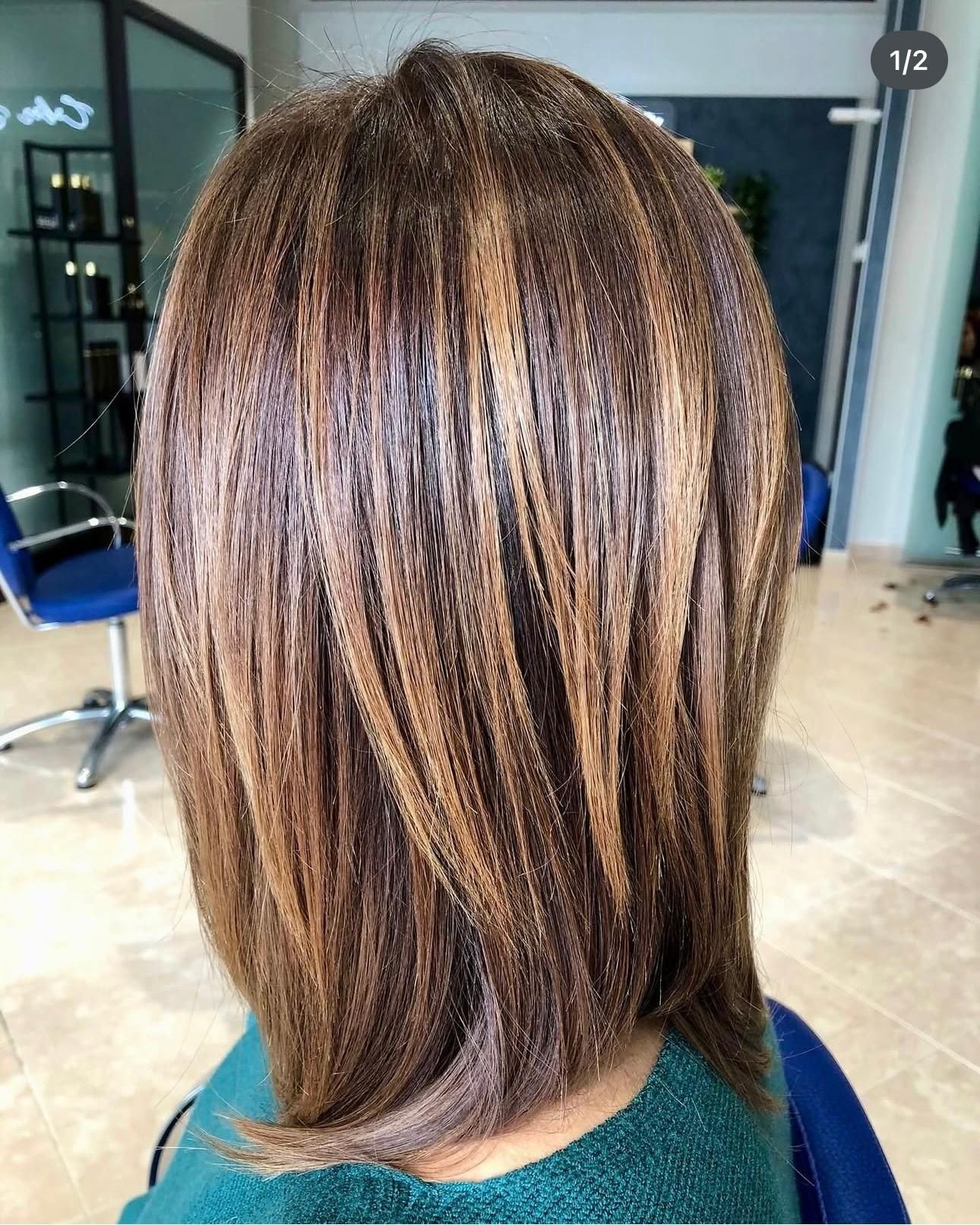 Taglio di capelli corto scalato con mèches castane, visto di spalle da una poltrona da parrucchiere.