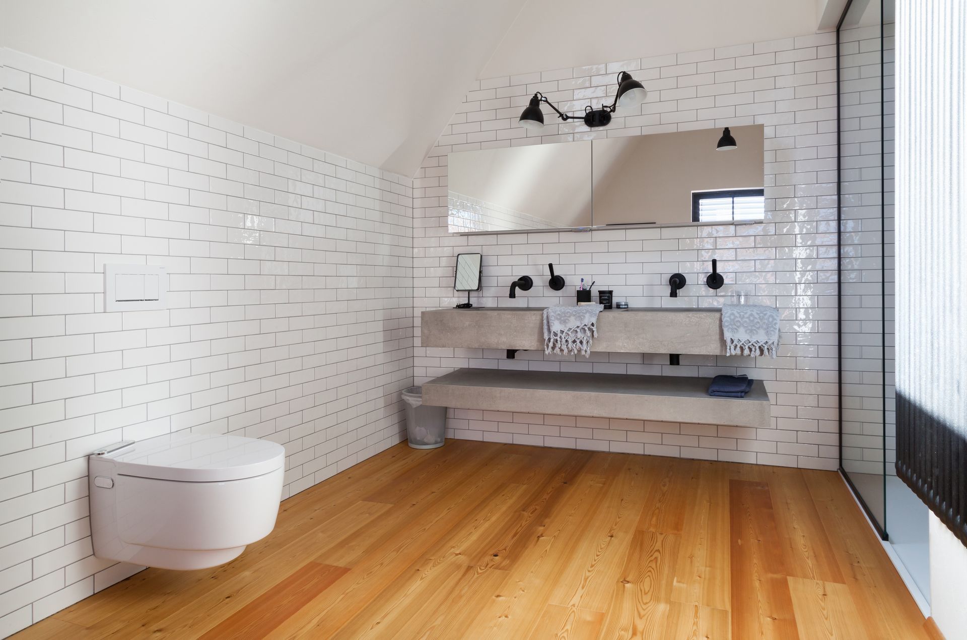Une salle de bain avec WC, lavabo, miroir et parquet.