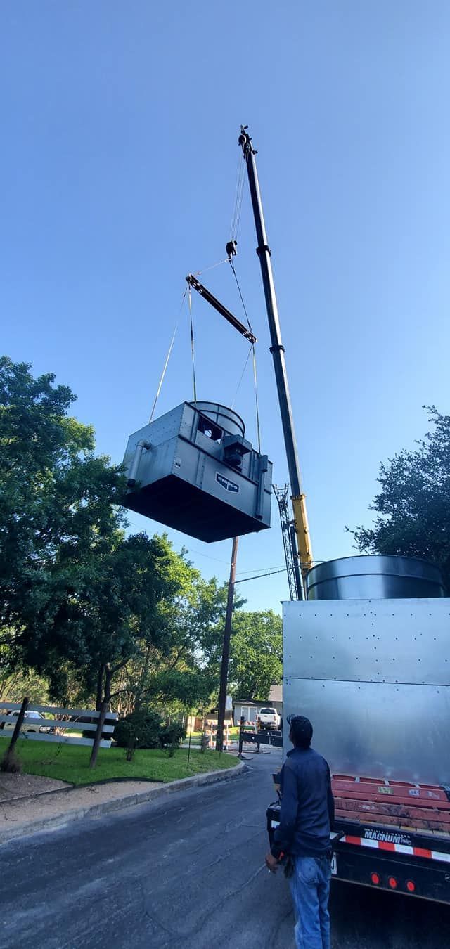 A man is standing next to a truck that is being lifted by a crane.