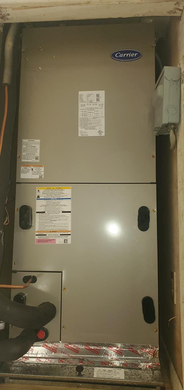 A carrier air conditioner is sitting in a corner of a room.