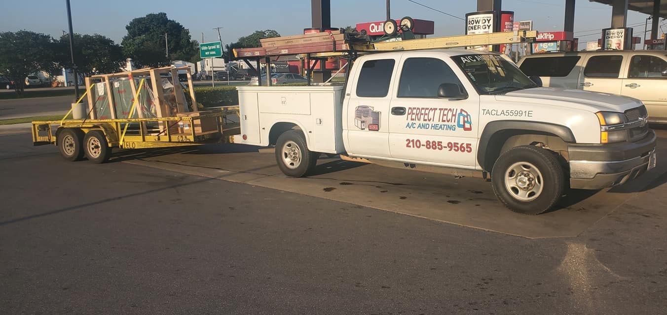 A white truck with a trailer attached to it is parked on the side of the road.