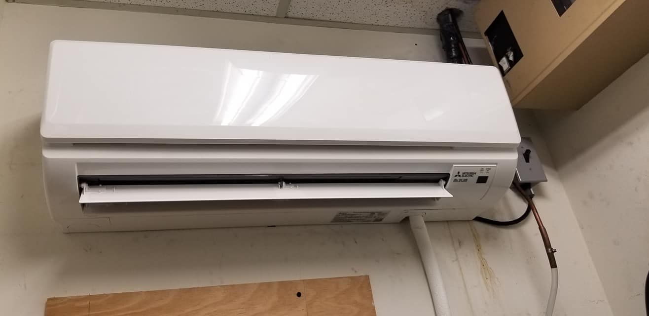 A white air conditioner is hanging on a wall in a room.