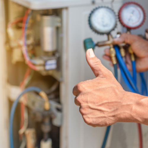 A person is giving a thumbs up while working on an air conditioner.