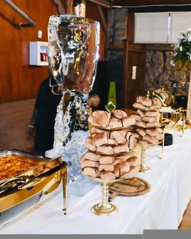 Buffet table with food, including donuts stacked on golden stands, and a decorative ice sculpture.