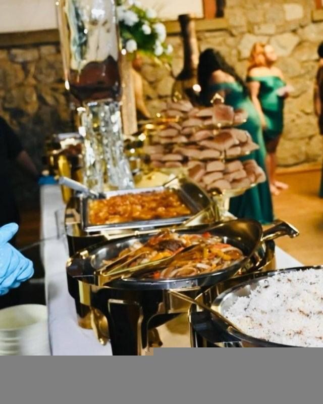 Buffet with various food items, including sandwiches and casseroles, set up indoors for an event. People are visible in the background.