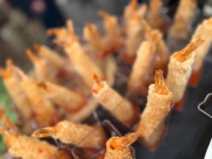 A bunch of fried shrimp on sticks on a table