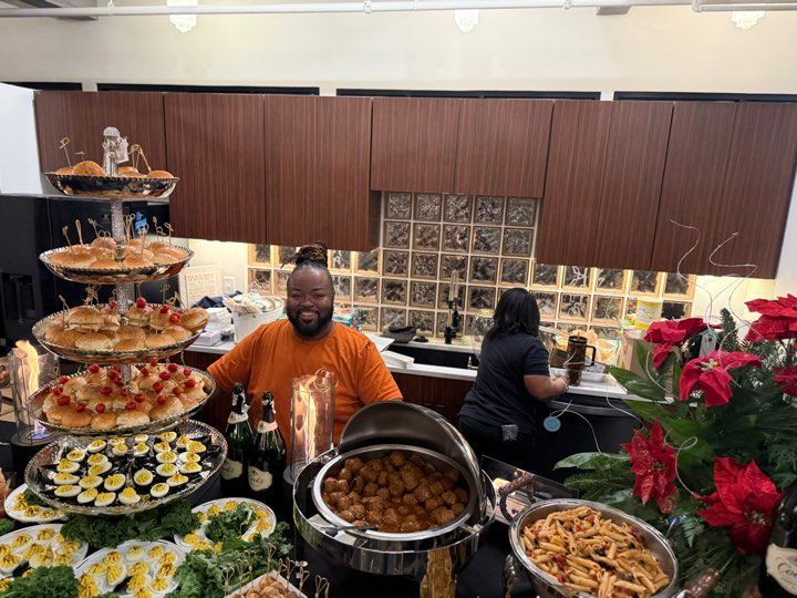 A man is standing in front of a buffet table filled with food.