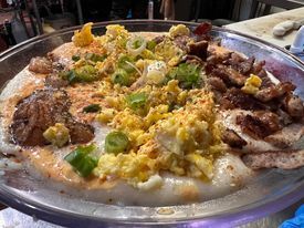 Large platter with scrambled eggs, meat, and sauce atop a bed of white bread.