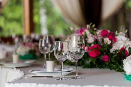 A table set for a celebration with wine glasses, floral arrangements, and a white tablecloth. A table set for a celebration with wine glasses, floral arrangements, and a white tablecloth.