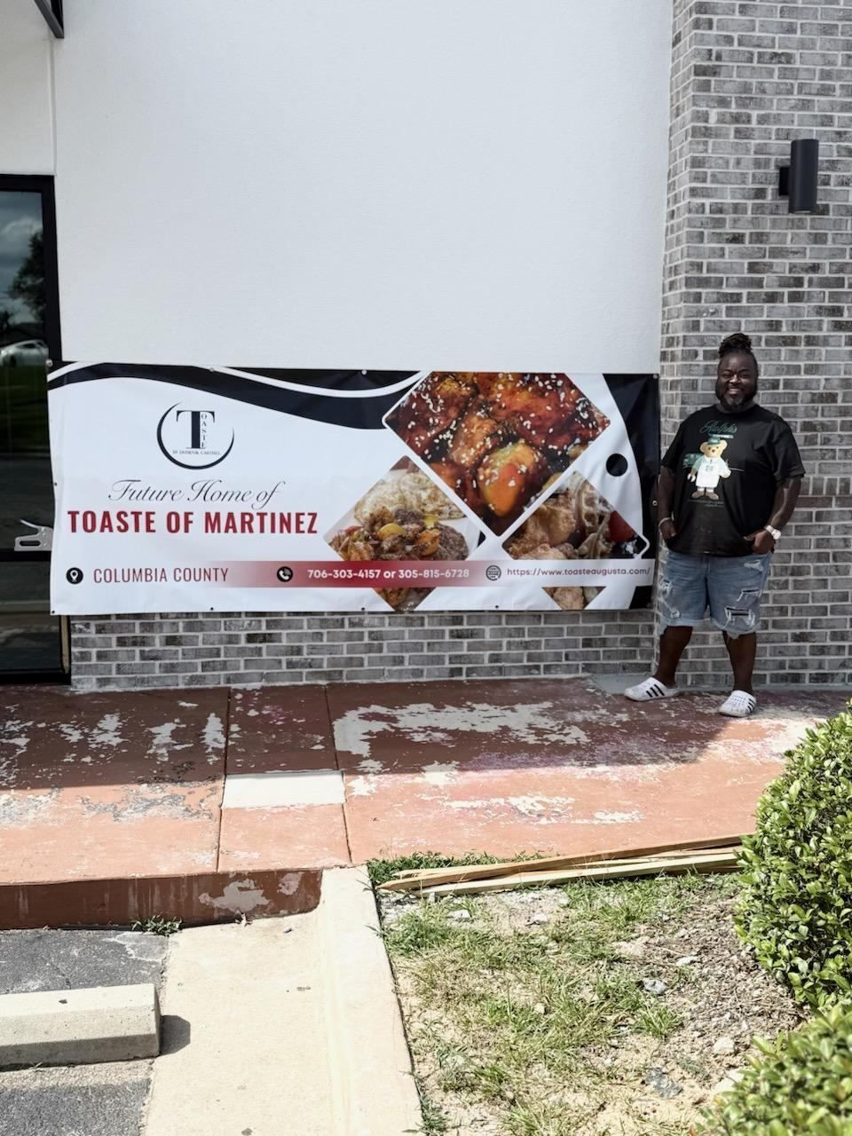 Man stands in front of a banner advertising 
