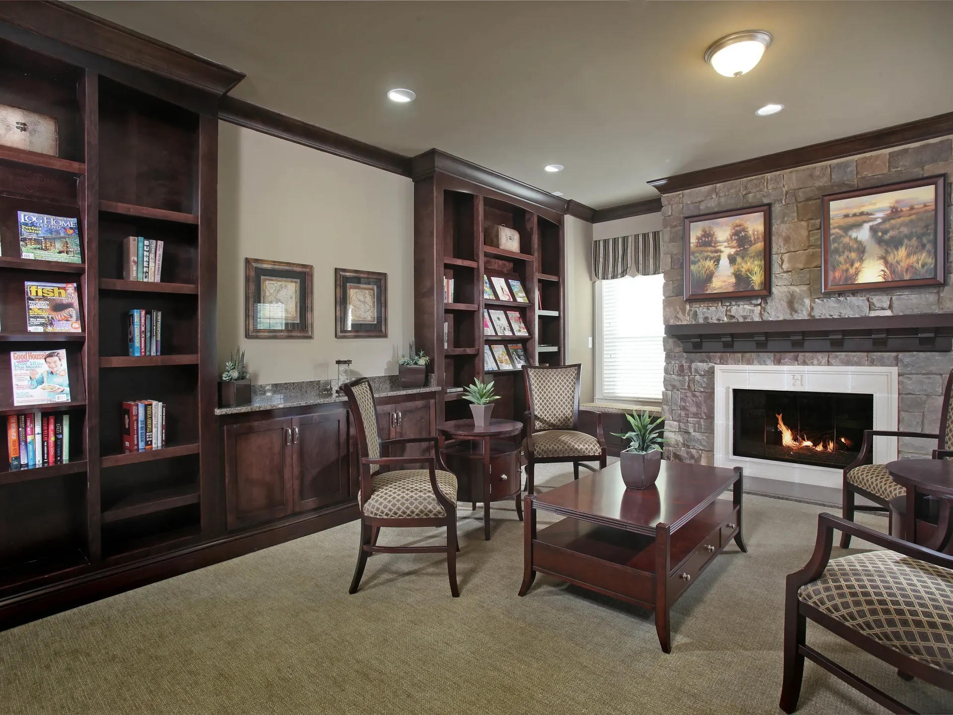 Community lounge with dark wood shelves, a stone fireplace, and seating.