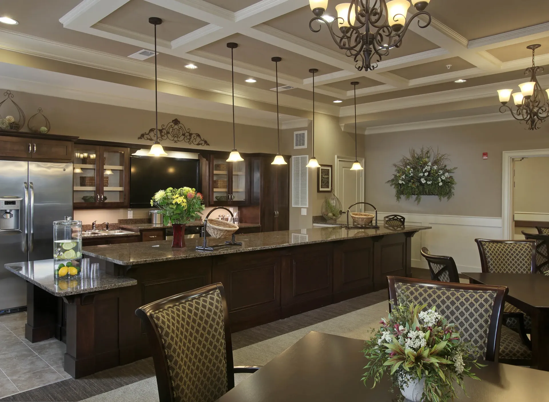 Interior community kitchen with dark wood cabinetry, granite counter, and pendant lighting.
