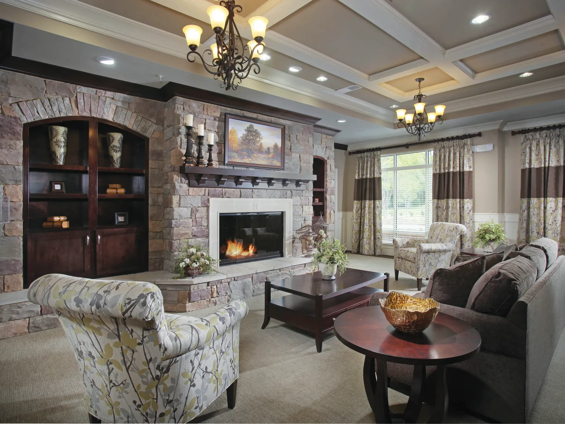 Stone fireplace lounge with plush seating and chandeliers.