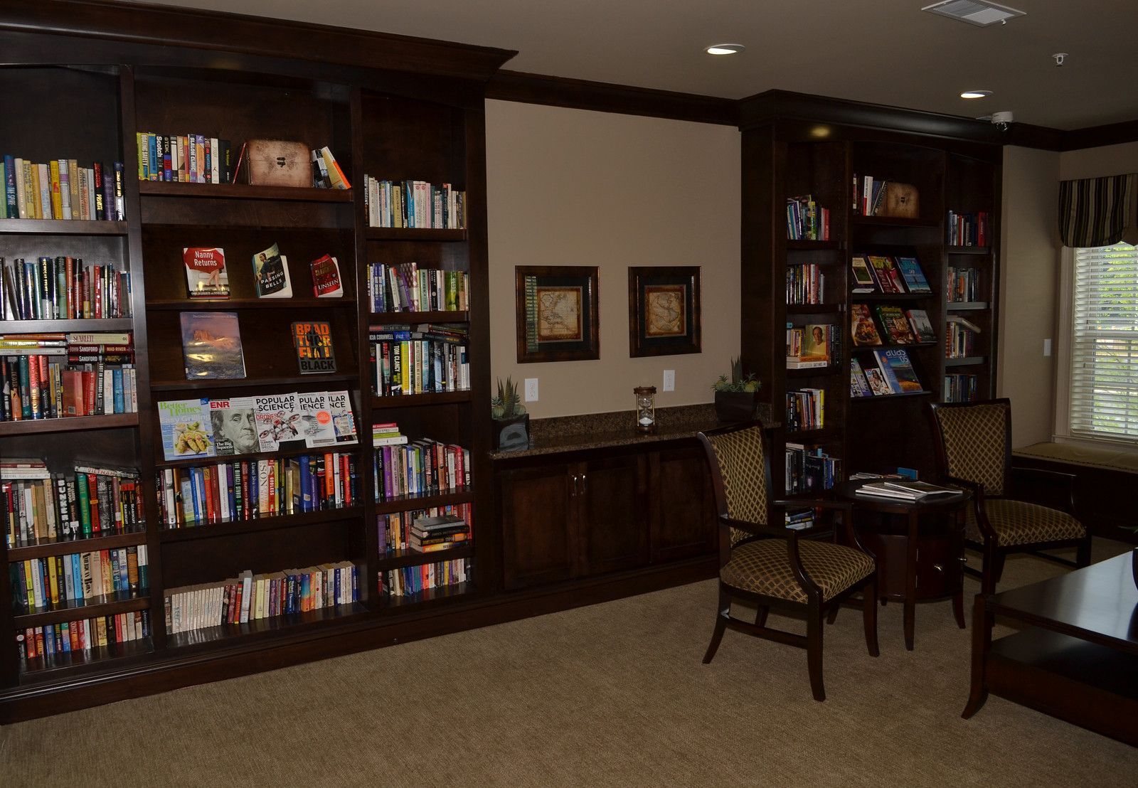 Library-style resident lounge with dark wood bookshelves, chairs, and a table.