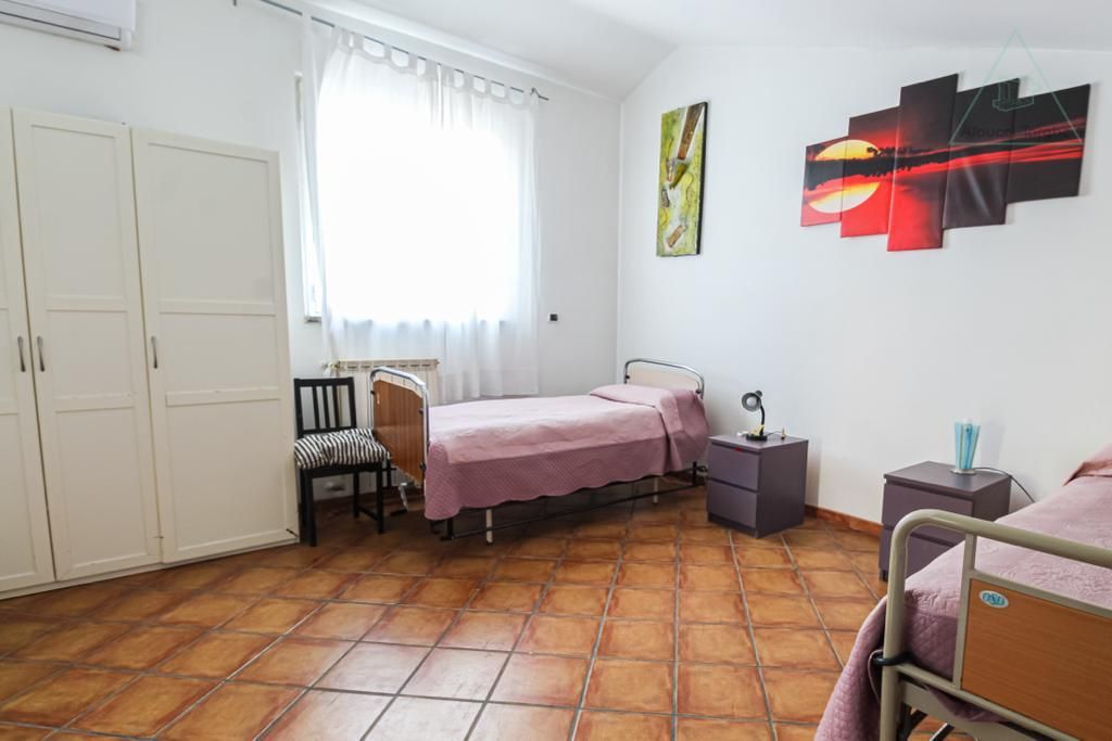 Una stanza d'ospedale con due letti e un comodino.