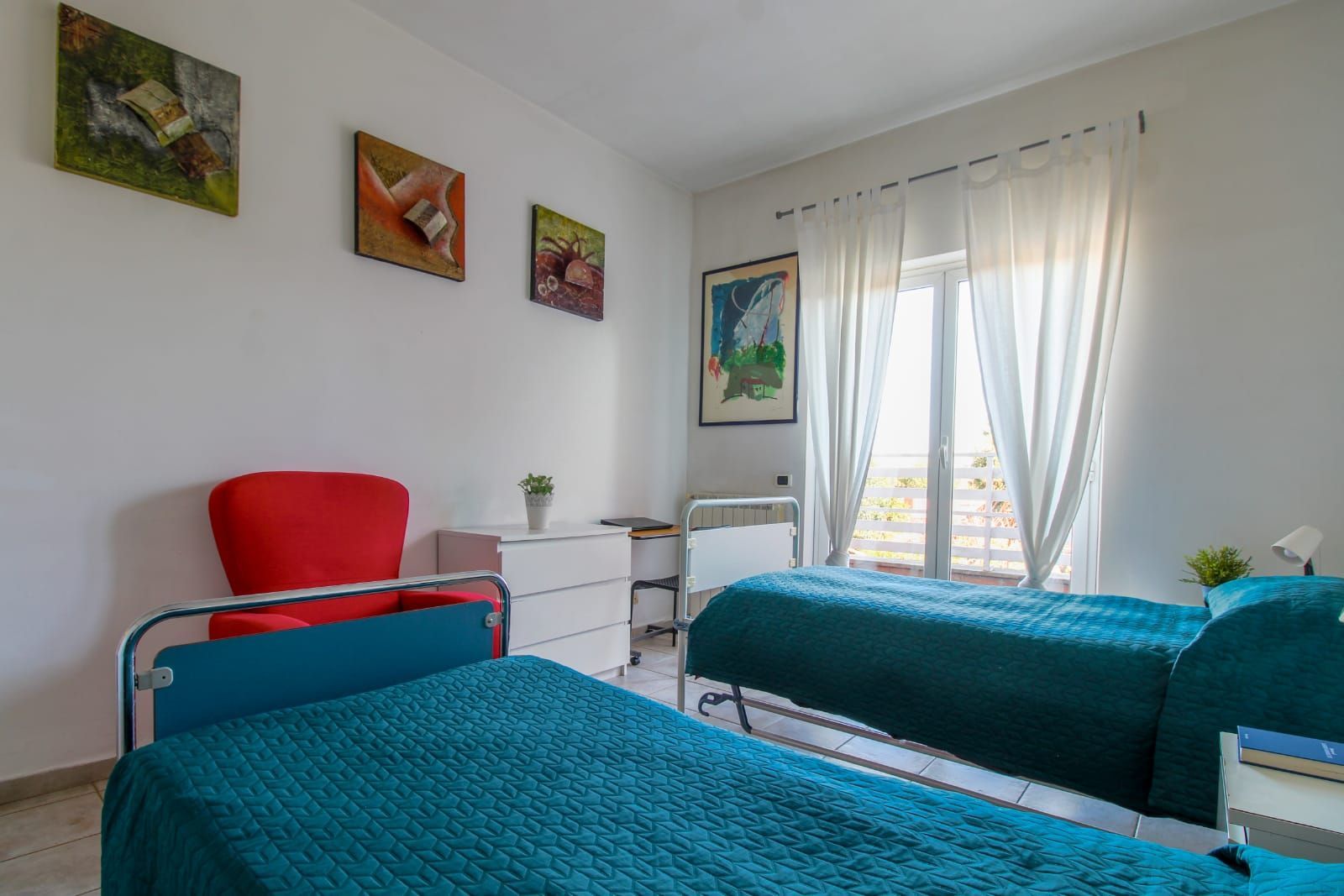 A bedroom with two beds , a chair and a window.