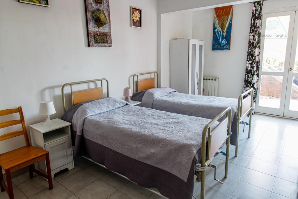 Una stanza d'ospedale con due letti e una sedia.