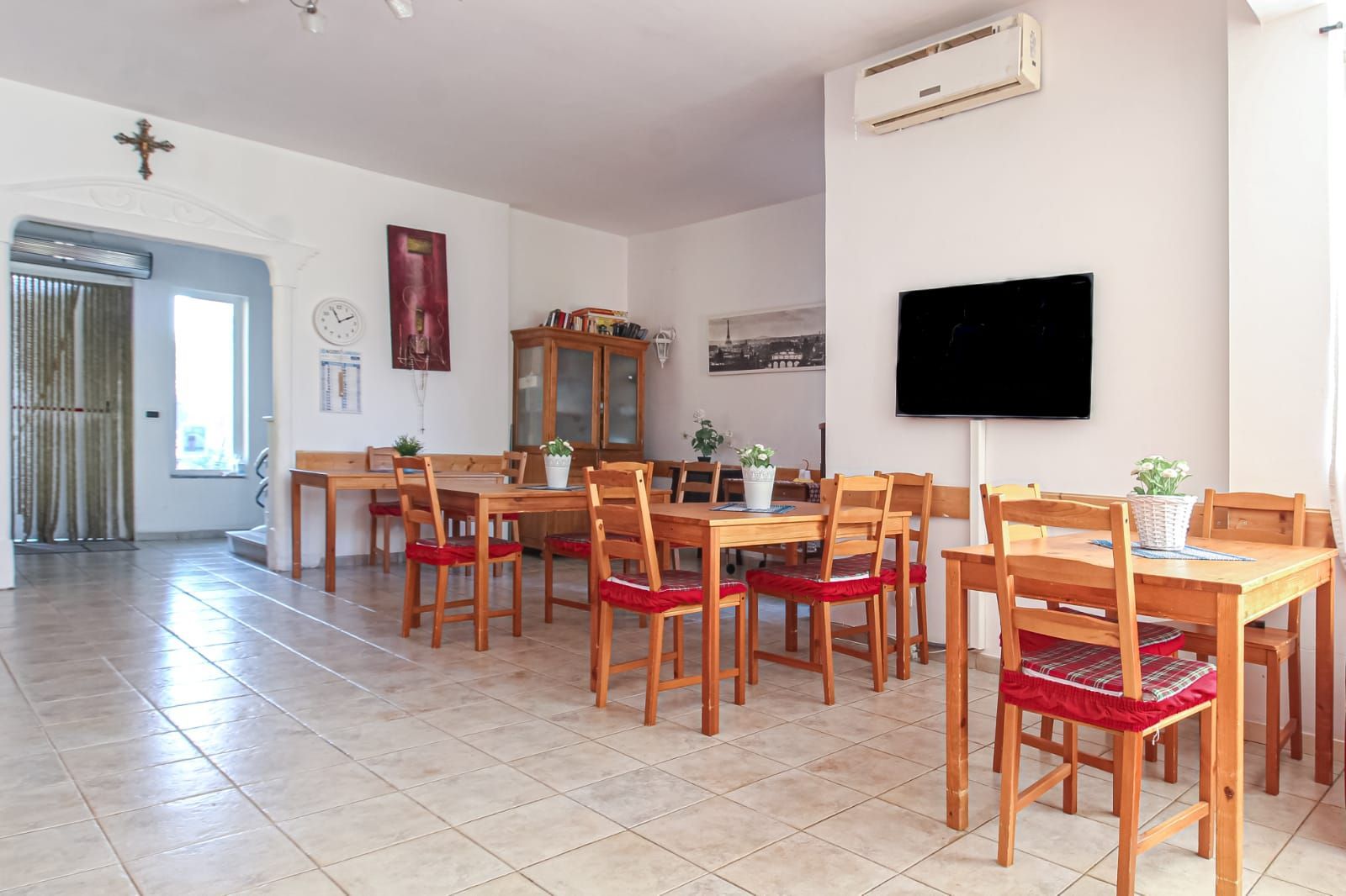 Una sala da pranzo con tavoli e sedie e una TV a schermo piatto.