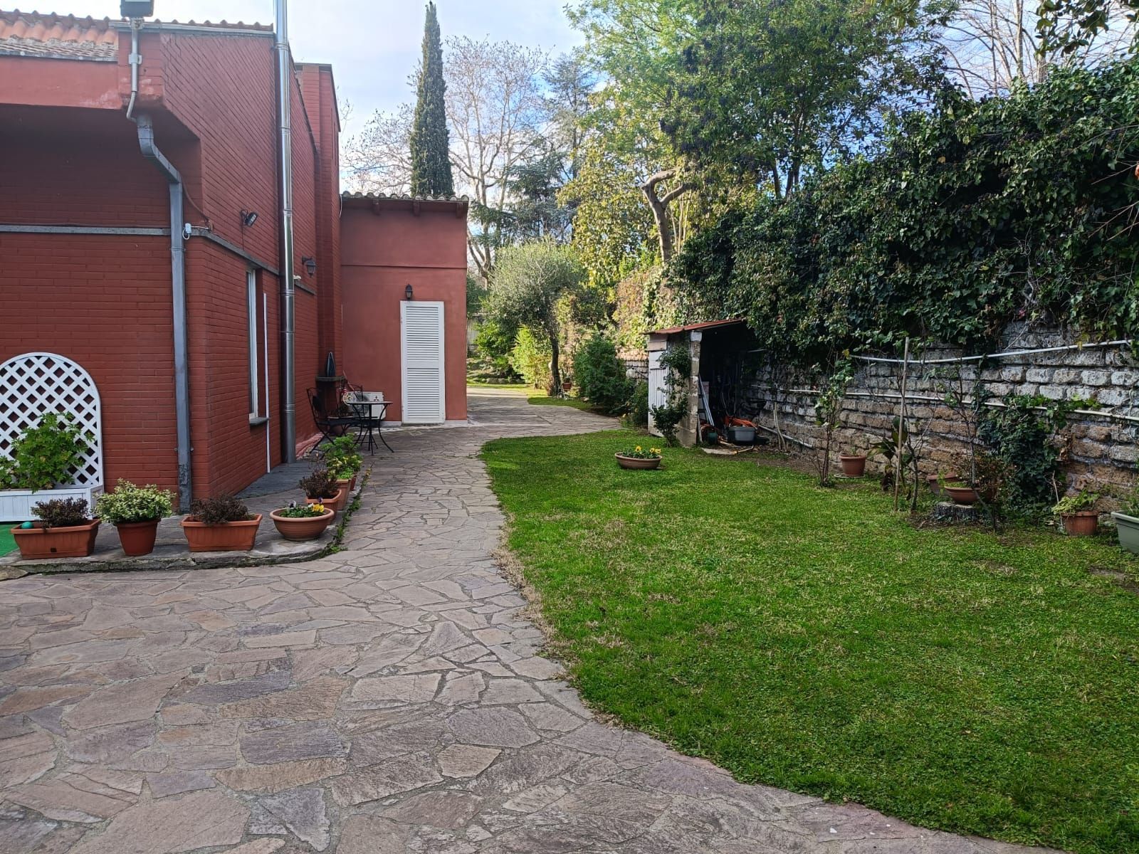 Una casa in mattoni con un rigoglioso cortile davanti.