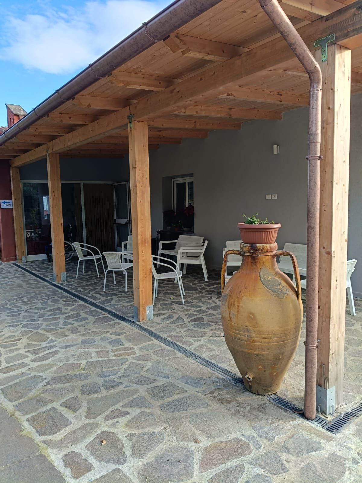 Un grande vaso è posto sotto un tetto di legno accanto a una passerella di pietra.