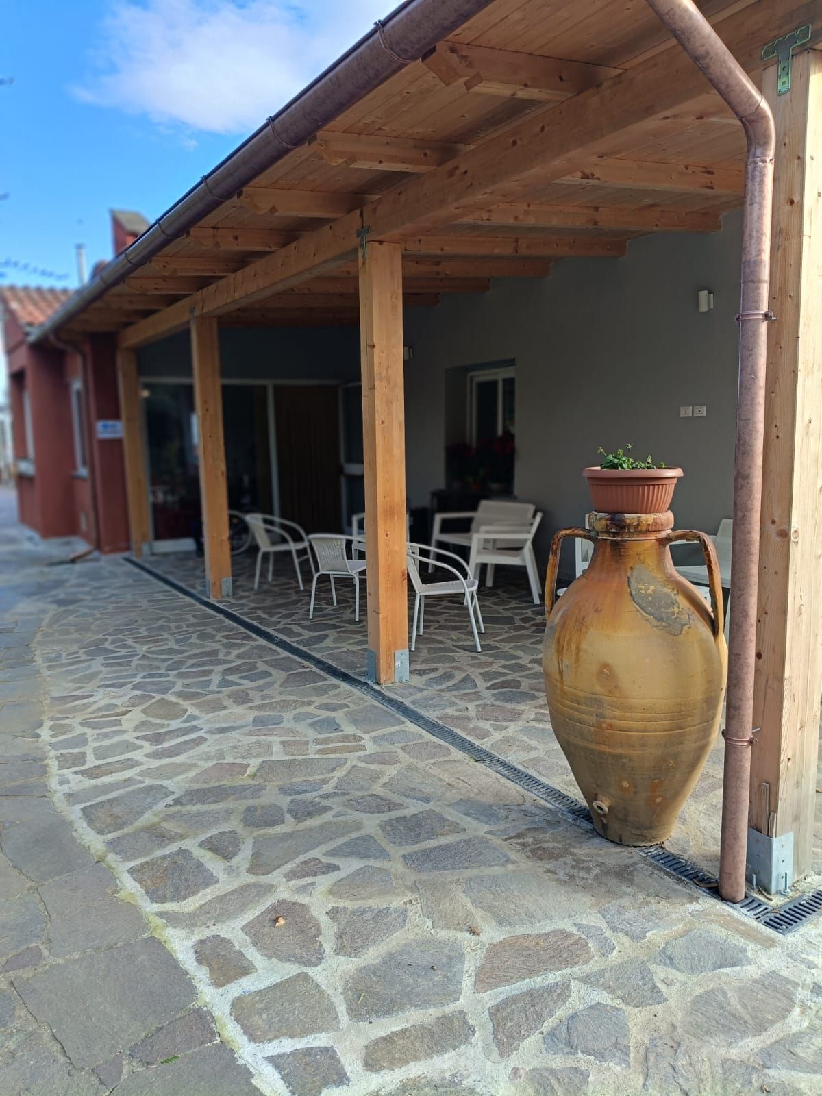 Un grande vaso è posto sotto un tetto di legno accanto a una passerella di pietra.