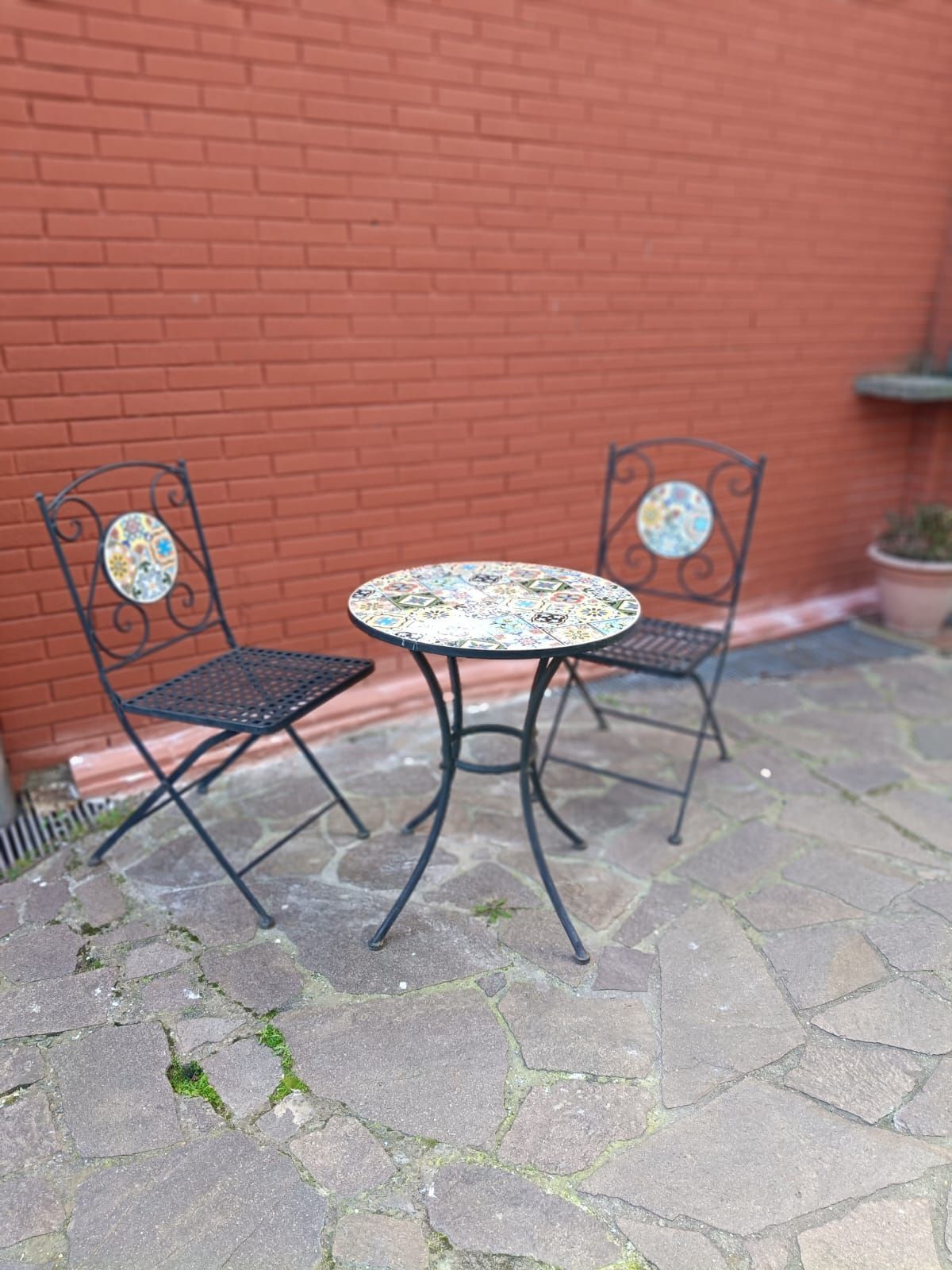 Un tavolo e delle sedie sono sistemati su un patio di fronte a un muro di mattoni.