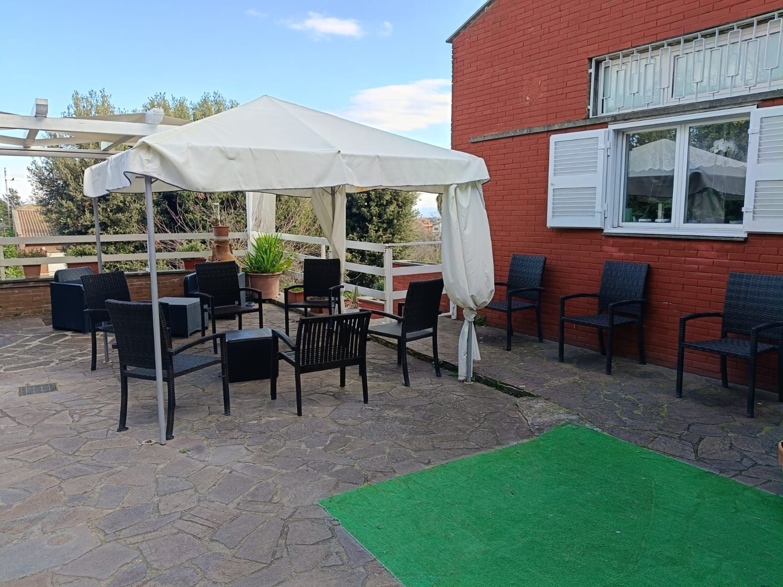Un patio con sedie, tavoli e ombrelloni di fronte a un edificio in mattoni.